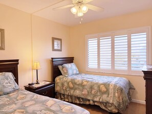 A bedroom with two beds, a ceiling fan, a window with blinds, and a nightstand with a lamp. - La Coquina Gulf-Front – Beach, Pool & Sunset Views (Englewood)