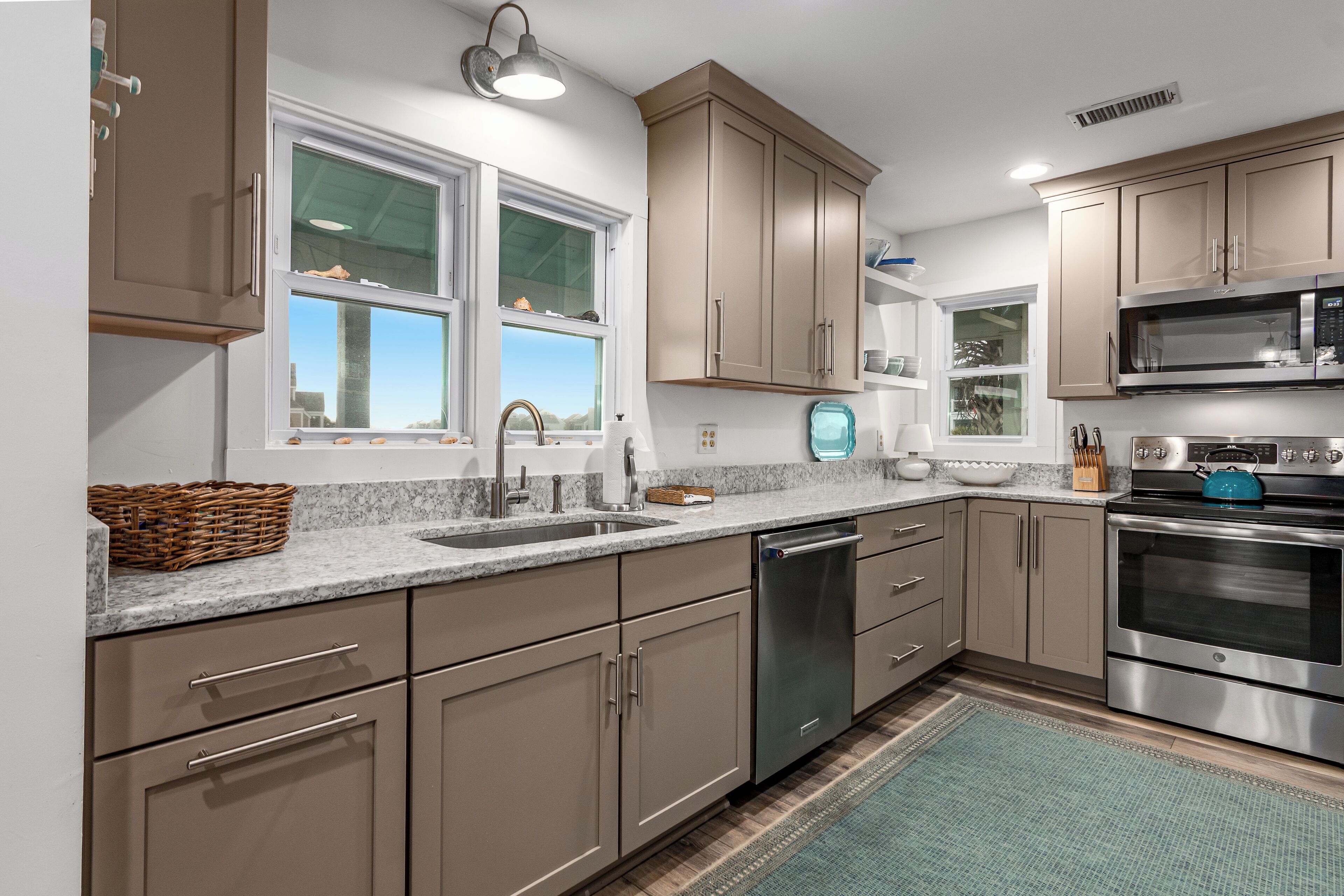 A modern kitchen with stainless steel appliances, beige cabinetry, and a window providing natural light.