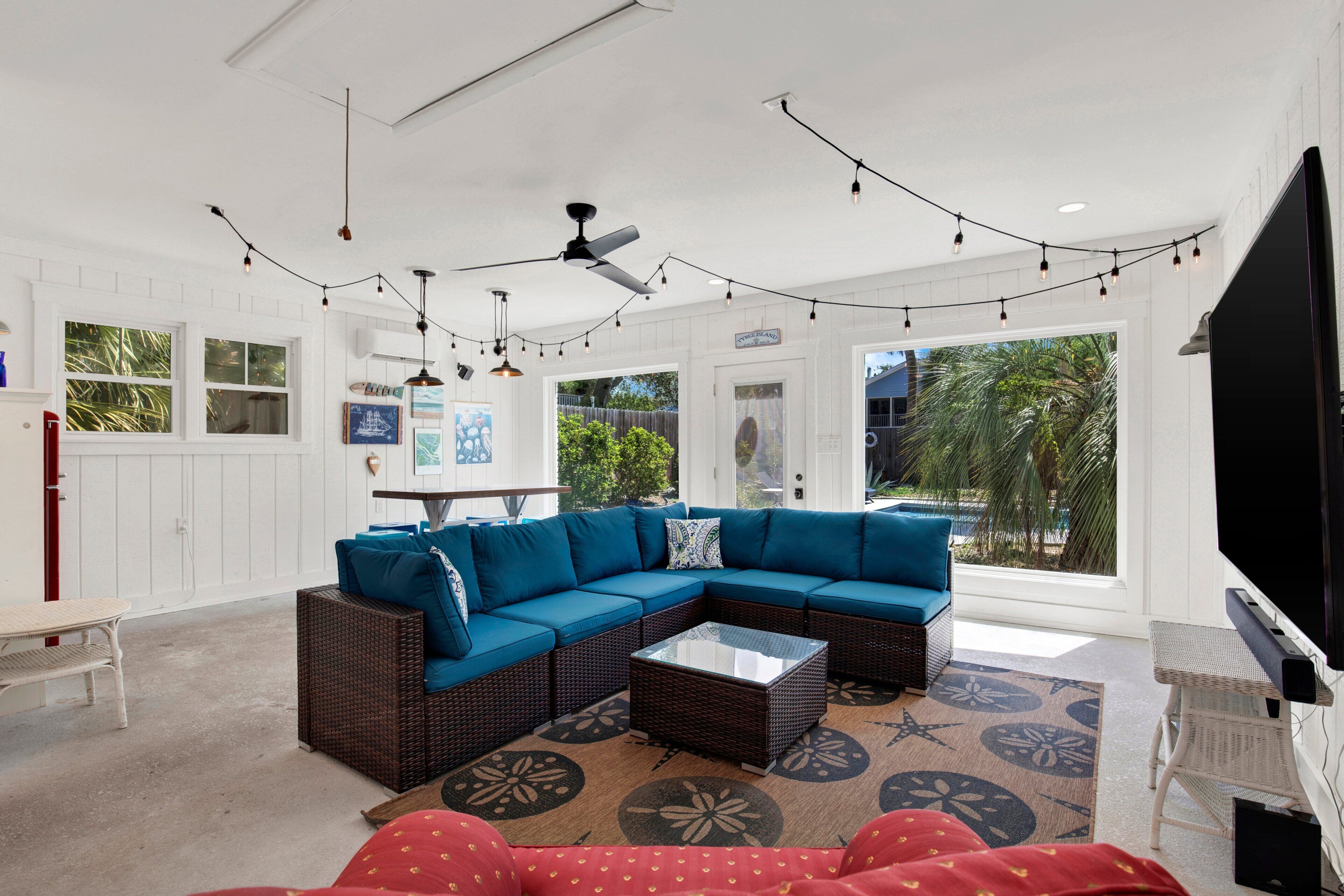 A spacious living area with a sectional sofa, a flat-screen TV, and string lights.