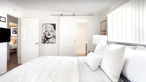 A hotel room with a large bed, white bedding, a framed picture on the wall, and a window with blinds. - Pool + Spa + Stargazing: Stylish Mid-Century Home Near Joshua Tree National Park (Twentynine Palms)