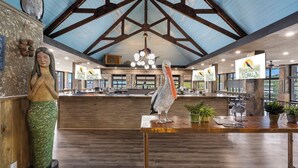 A restaurant interior with a high ceiling, wooden beams, and a central bar area.