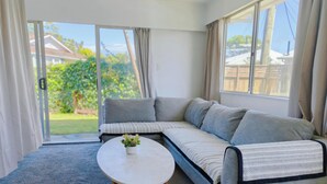 A modern living room with a sectional sofa, a round coffee table, and a view of the outdoors. - Comfortable stay for 6 / Perfect for family trip (Lower Hutt)