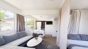 A compact room with a sofa, a small table, a TV, and a bed. - Comfortable stay for 6 / Perfect for family trip (Lower Hutt)