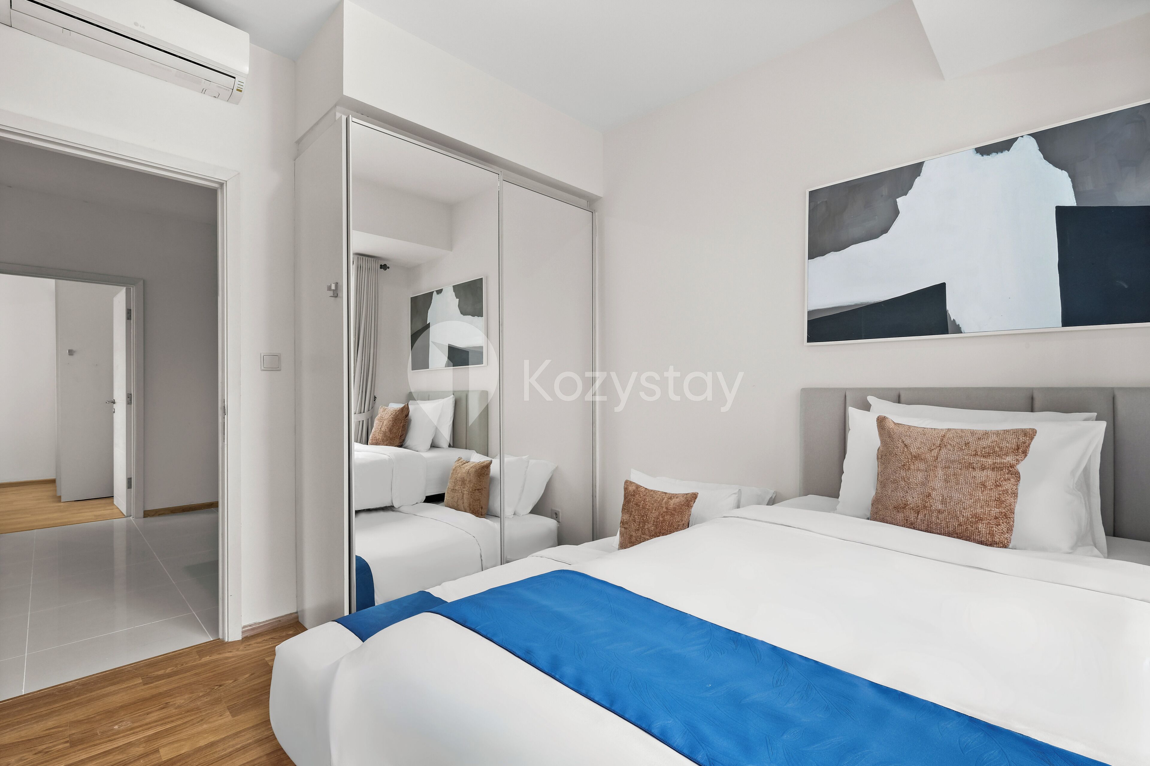 A modern hotel room with a large bed, a walk-in closet, and a large abstract painting on the wall.