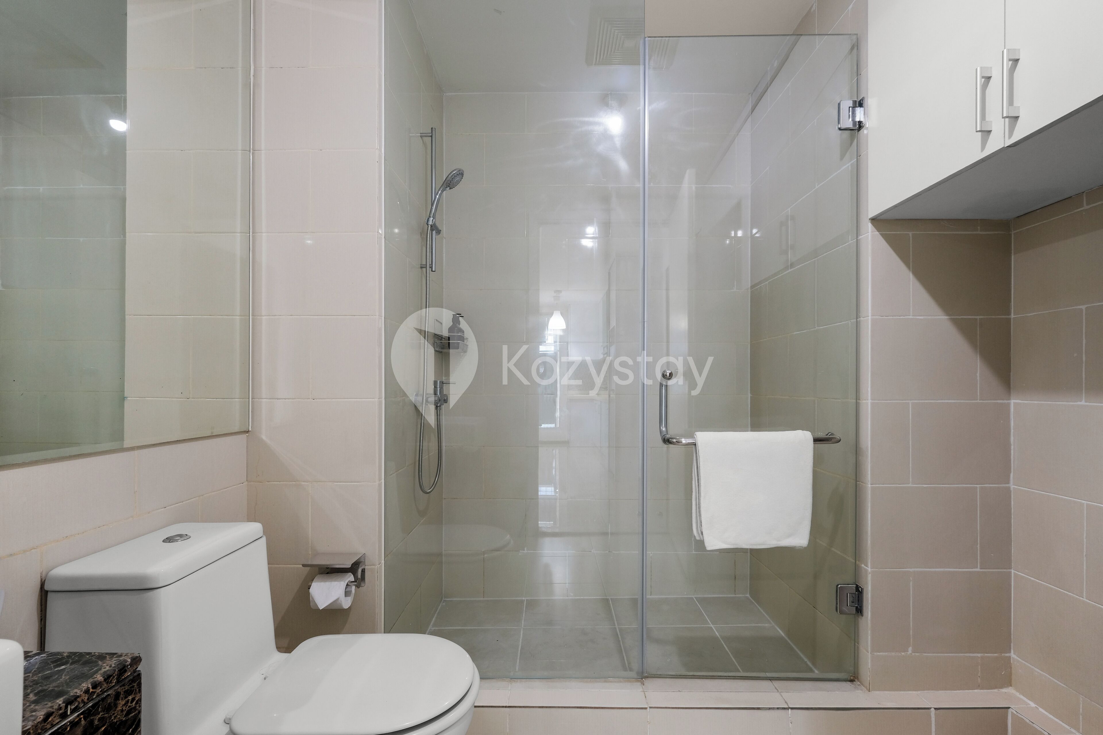 Un baño moderno con cabina de ducha de vidrio, inodoro y encimera de mármol.