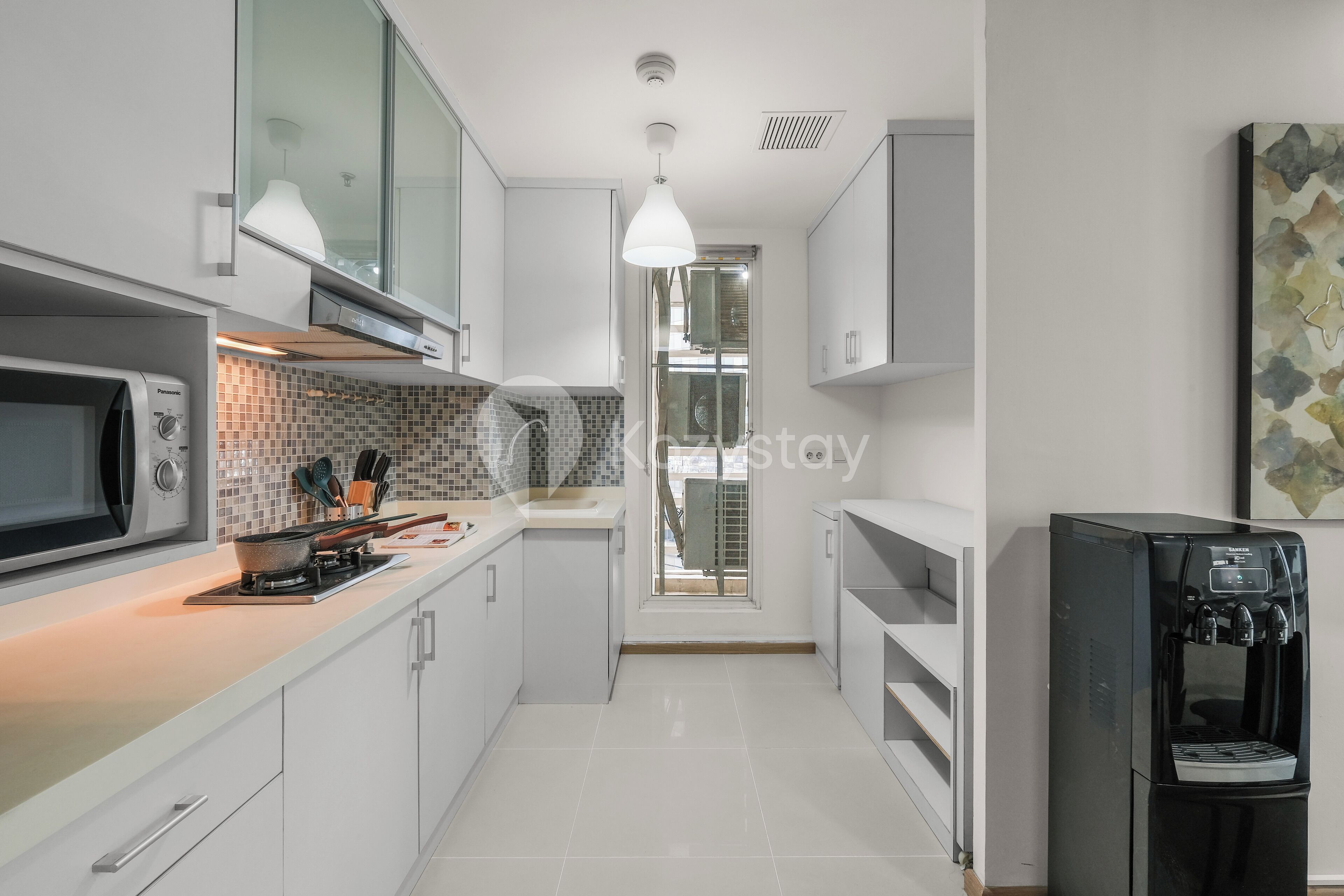 A modern kitchen with white cabinetry, a built-in microwave, a stove, and a water dispenser.