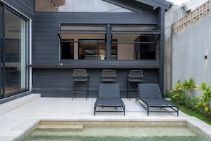 A modern outdoor pool area with three lounge chairs and a small pool. - Black Villa by Betterplace (Tabanan)