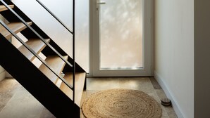 A modern interior with a staircase, a sliding glass door, and a woven rug. - Renovated farmhouse with swimming pool, pétanque and country views (Coufouleux)