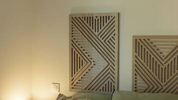 Un dormitorio con cama, almohadas, una lámpara fijada a la pared y un panel de madera decorativo.
