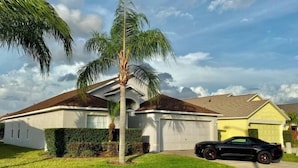 A residential house with a garage, a lawn, and a parked sports car.
