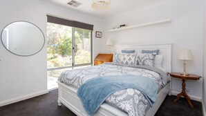 Un dormitorio con una cama grande, un espejo redondo, una ventana y una mesita de noche con lámpara.