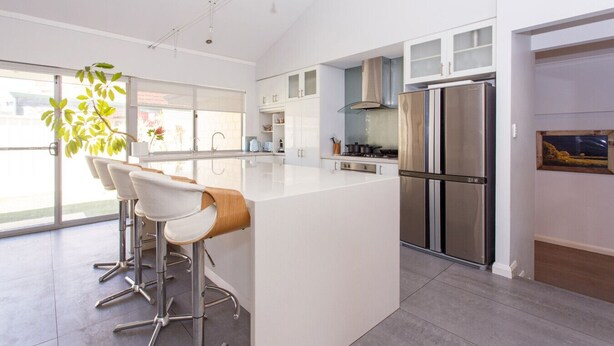 Una cocina moderna con una isla central, electrodomésticos de acero inoxidable y un ventanal grande.