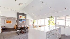 Una cocina moderna con una isla grande, comedor con sillas y obras de arte en las paredes.