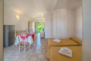 A room with a bed, a table with chairs, a refrigerator, and a view of greenery outside. - Borgo Primizia M17 Pool And Sea, Otranto, Italy (Otranto)