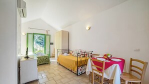 A bedroom with a bed, bedside table, and a small desk with a chair. There is a window with curtains, a wardrobe, and a table with chairs. - Borgo Primizia M16 Pool And Sea, Otranto, Italy (Otranto)