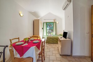 Ein Essbereich mit Tisch für zwei Personen, einem Bett mit grüner Bettdecke und einem Schreibtisch mit Computer.