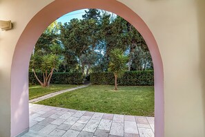 An arched pathway leading to a well-maintained garden with various trees and a hedge. - Borgo Primizia M13 Pool And Sea, Otranto, Italy (Otranto)