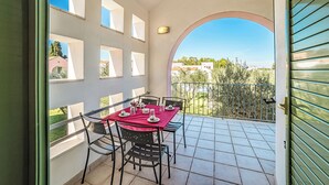 Ein Balkon mit Esstisch, gedeckt mit einer roten Tischdecke und Stühlen.