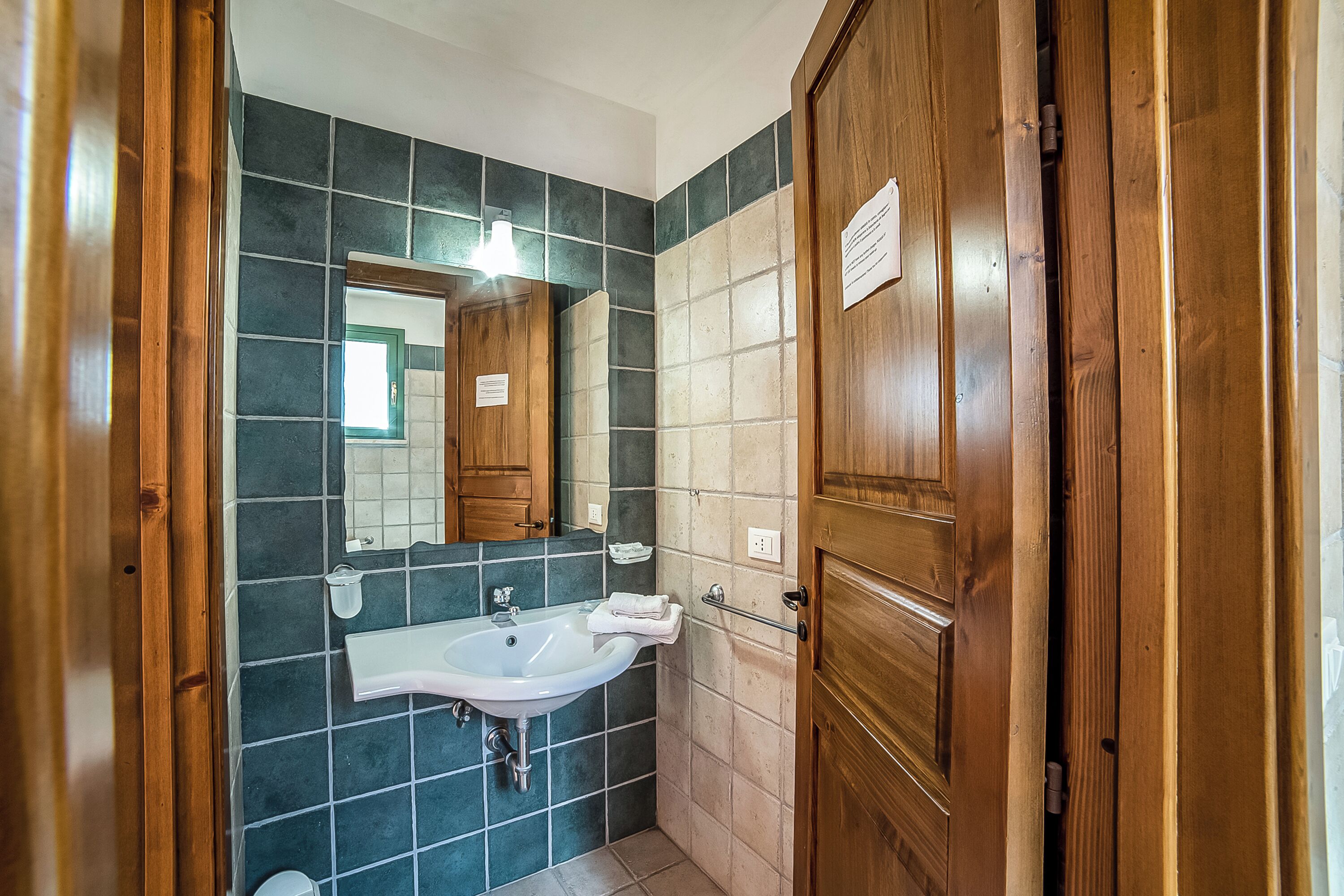 A bathroom with a sink, mirror, and wooden door.