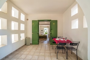 A dining area with a red table and black chairs, a green door leading to another room, and a tiled floor. - Borgo Primizia M9 Pool And Sea, Otranto, Italy (Otranto)