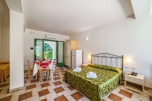 A room with a bed, a table with chairs, a refrigerator, and a bedside table with a phone. - Borgo Primizia M9 Pool And Sea, Otranto, Italy (Otranto)