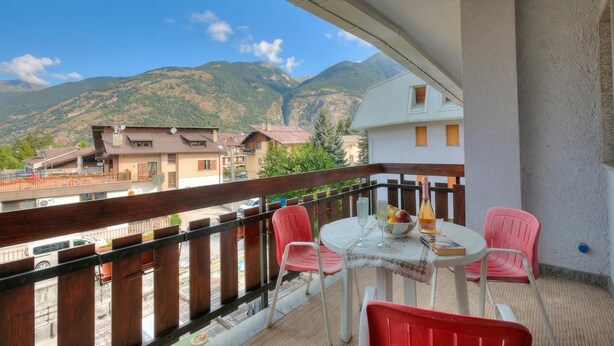 Un balcon avec une table, des chaises et une vue sur les montagnes.