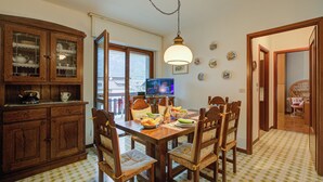 Un coin repas comprenant une table en bois, des chaises, un buffet et un téléviseur.