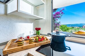A kitchen with a view of the sea, a wooden countertop with food items, and a kettle. - Aironi 34, Porto Rotondo, Italy (Porto Rotondo)