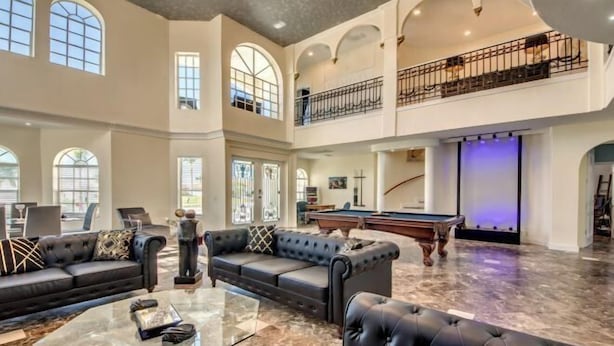 A spacious living area with a pool table, leather sofas, and a glass coffee table. - Golden Globe - luxury on the canal with pool/spa (Cape Coral)