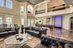 A spacious living area with a pool table, leather sofas, and a glass coffee table. - Golden Globe - luxury on the canal with pool/spa (Cape Coral)
