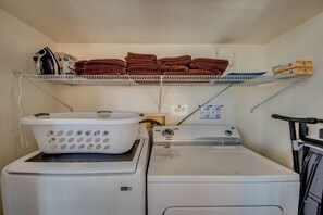 A laundry area with stacked towels, a white washing machine, and a dryer. - Golden Globe - luxury on the canal with pool/spa (Cape Coral)