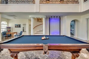 A pool table in a spacious room with a staircase and a seating area. - Golden Globe - luxury on the canal with pool/spa (Cape Coral)