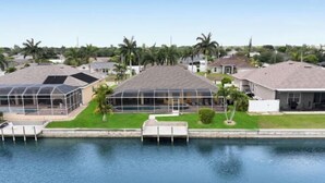 A residential area with houses, a swimming pool, and a greenhouse structure. - Casa de La Vista – Pool & Spa with lakefront view (Cape Coral)