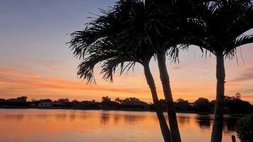 A calm lake at sunset with palm trees in the foreground.
