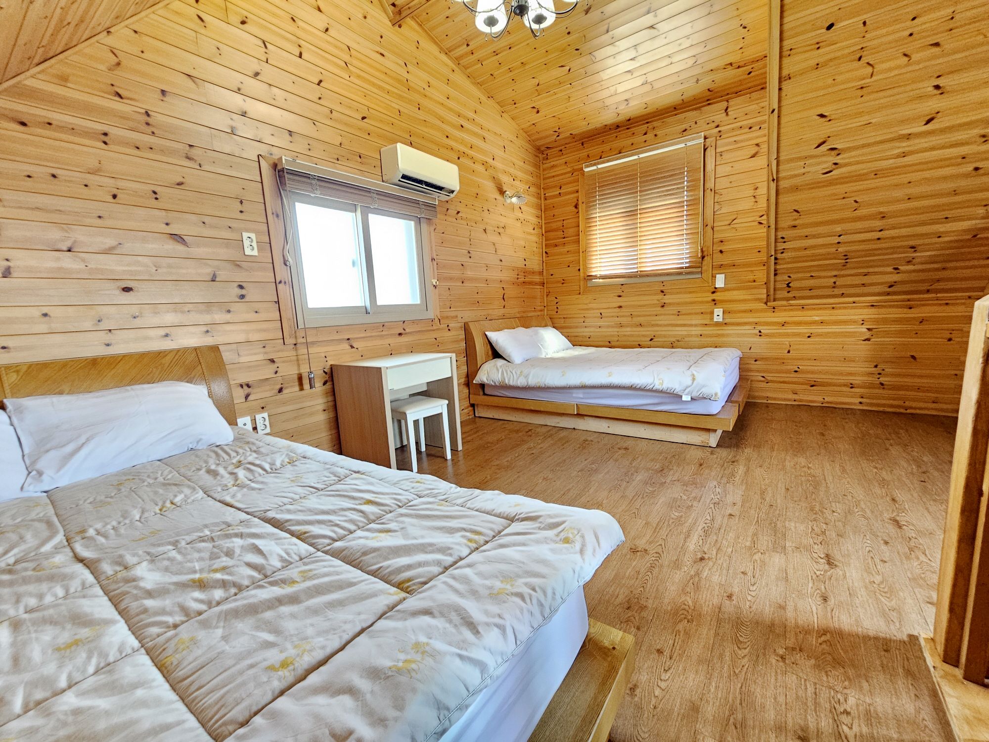A cabin with two beds, a desk, and a window.