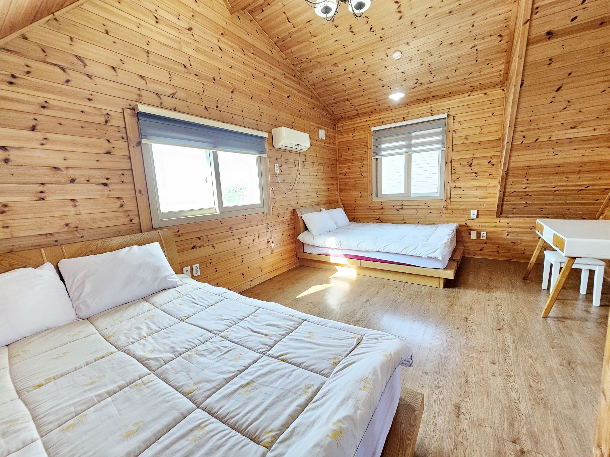 Une cabane en bois avec deux lits, un bureau et une fenêtre.