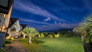 A residential area with a well-maintained lawn, pathway leading to a house, and a clear sky. - Zain Village pension (Seogwipo)