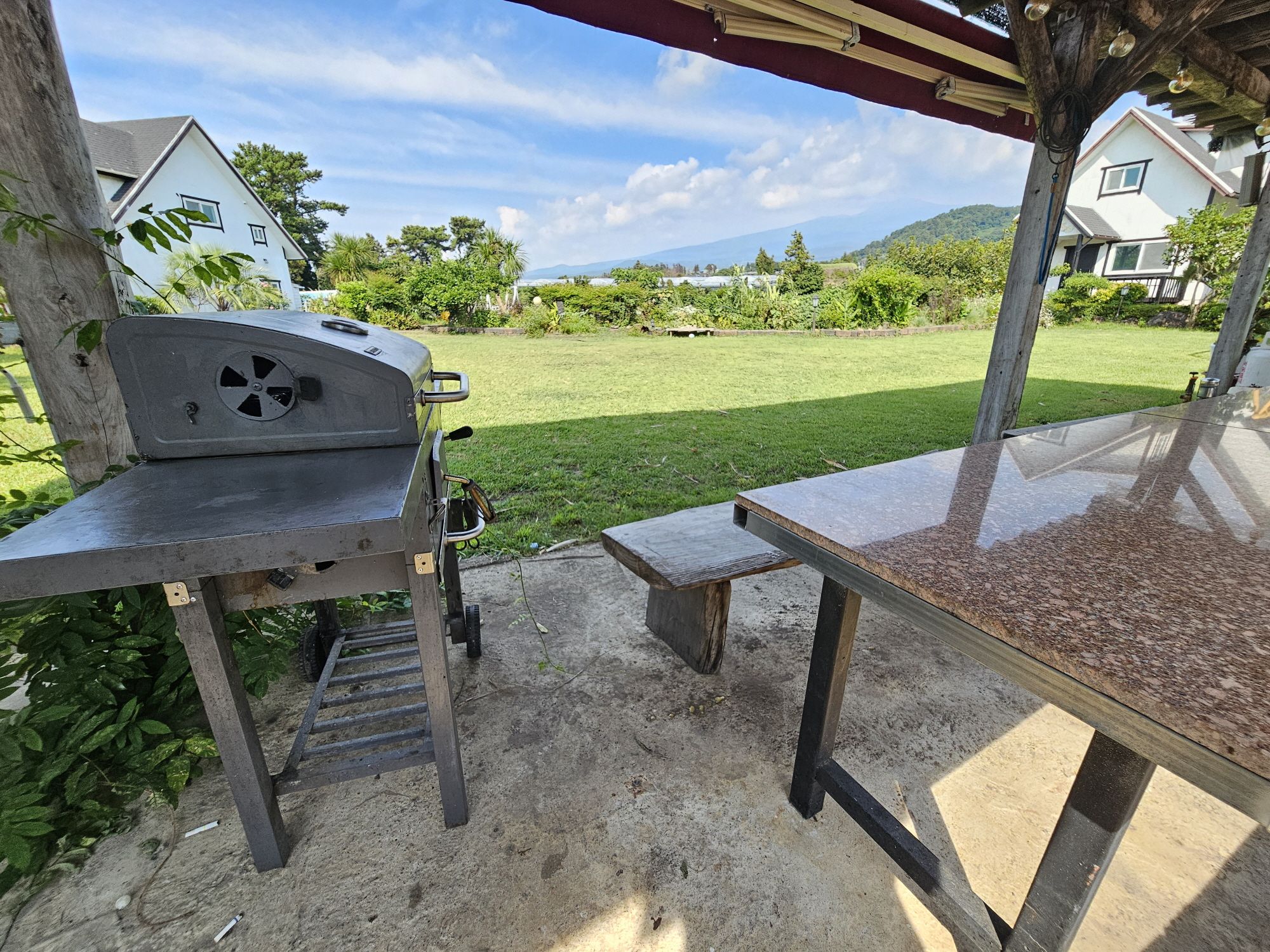 Un patio al aire libre con una parrilla, una mesa y un banco.