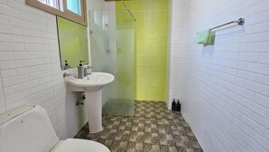 A bathroom with a white toilet, a sink, and a shower enclosure. - Zain Village pension (Seogwipo)
