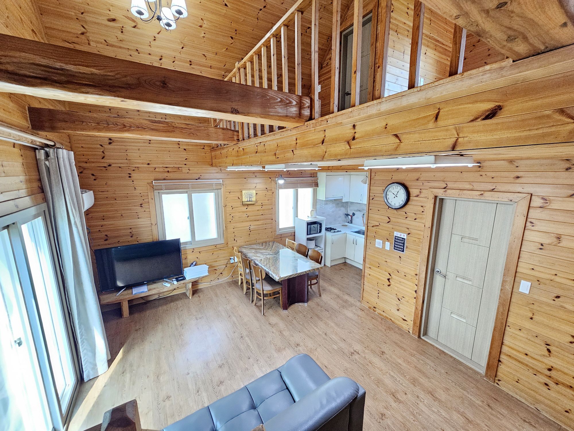 Interior de una cabaña con comedor, cocina y sala de estar con televisor.