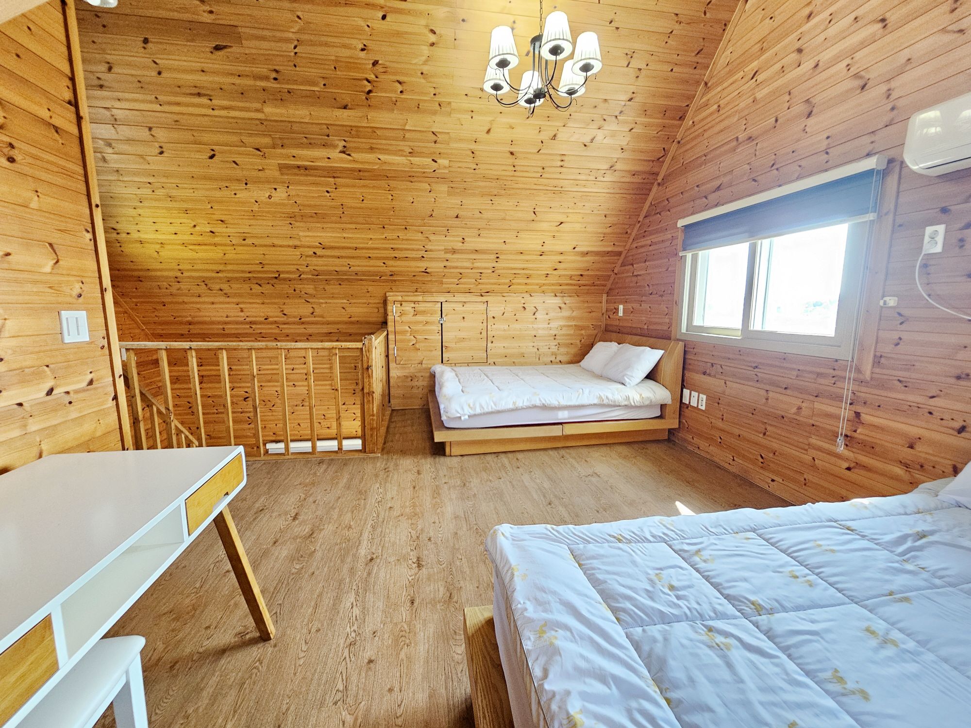 Un dormitorio de cabaña de madera con literas, un escritorio y una ventana.