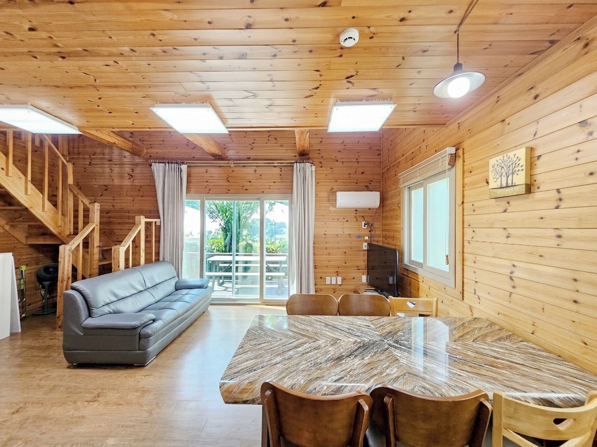 Un interior de madera con sofá, mesa de comedor, sillas y una escalera.