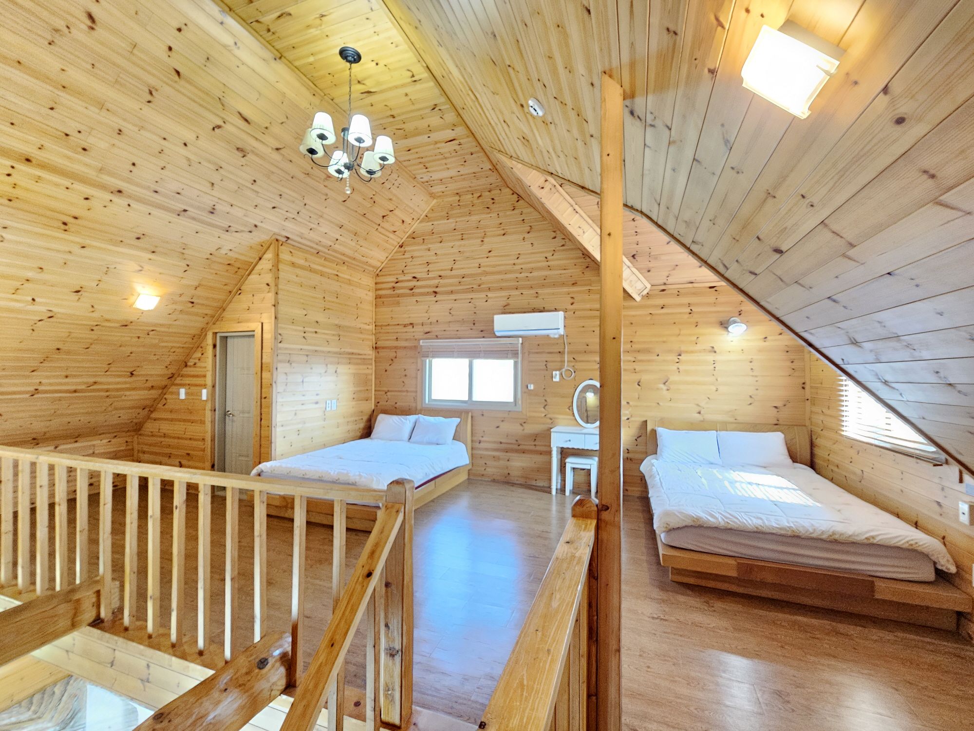 A wooden cabin with two bedrooms, a balcony, and a loft area.