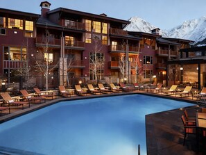 A resort with a pool surrounded by lounge chairs, a mountain backdrop, and a multi-story building with balconies. - Cozy 1-bedroom lodge in perfect Park City with AC and fitness room (Park City)