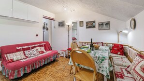 A cozy dining area with a wooden table set for four, surrounded by wooden chairs and a red sofa. - Appartamento La Selva Incantata, Sauze d'Oulx, Italy (Sauze d'Oulx)