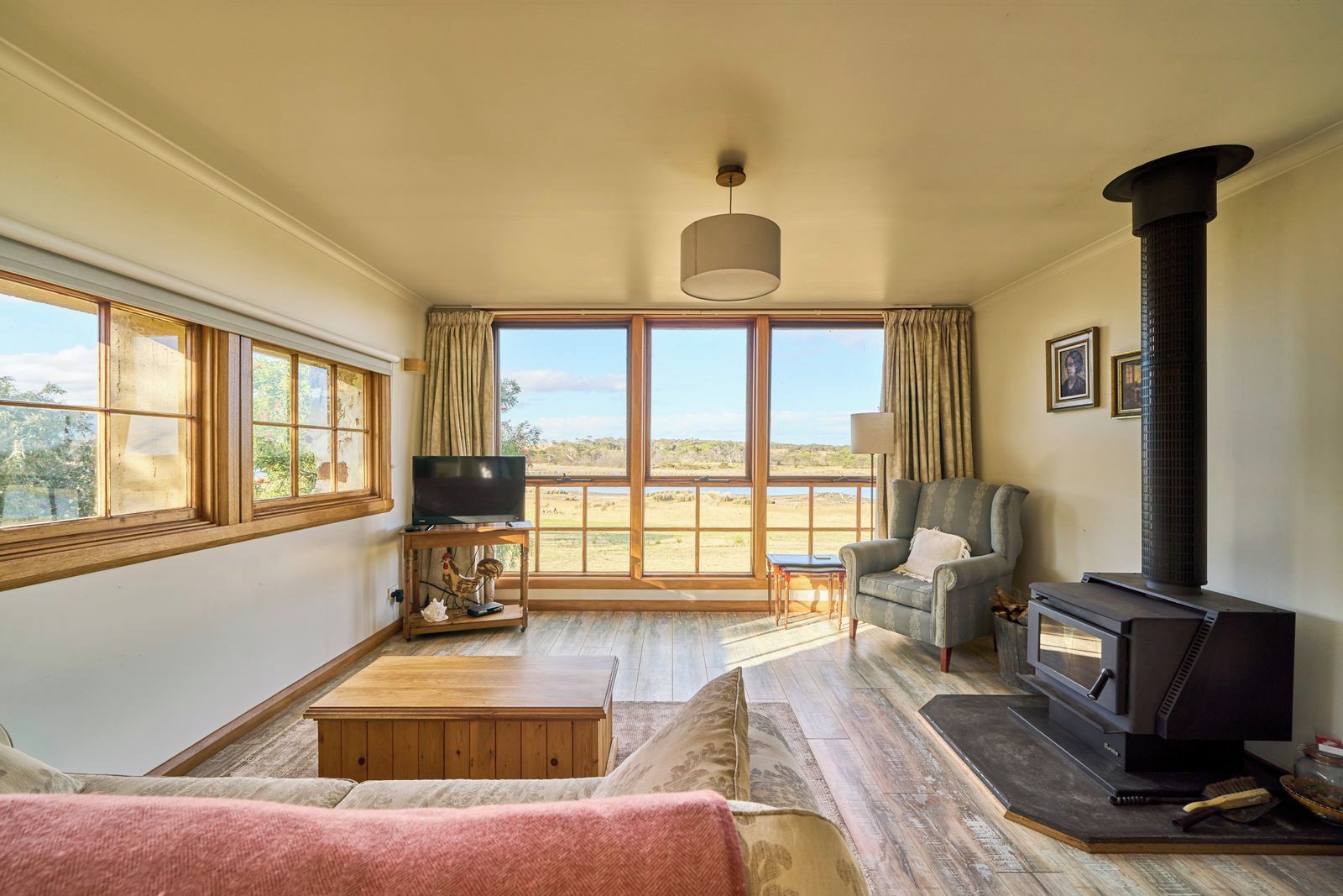 A spacious living room with a large window, a fireplace, a sofa, and a television.