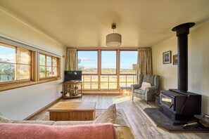 Un salón amplio con un gran ventanal, chimenea, sofá y televisor.