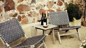 Outdoor wicker furniture with a table, a wine bottle, and a glass.