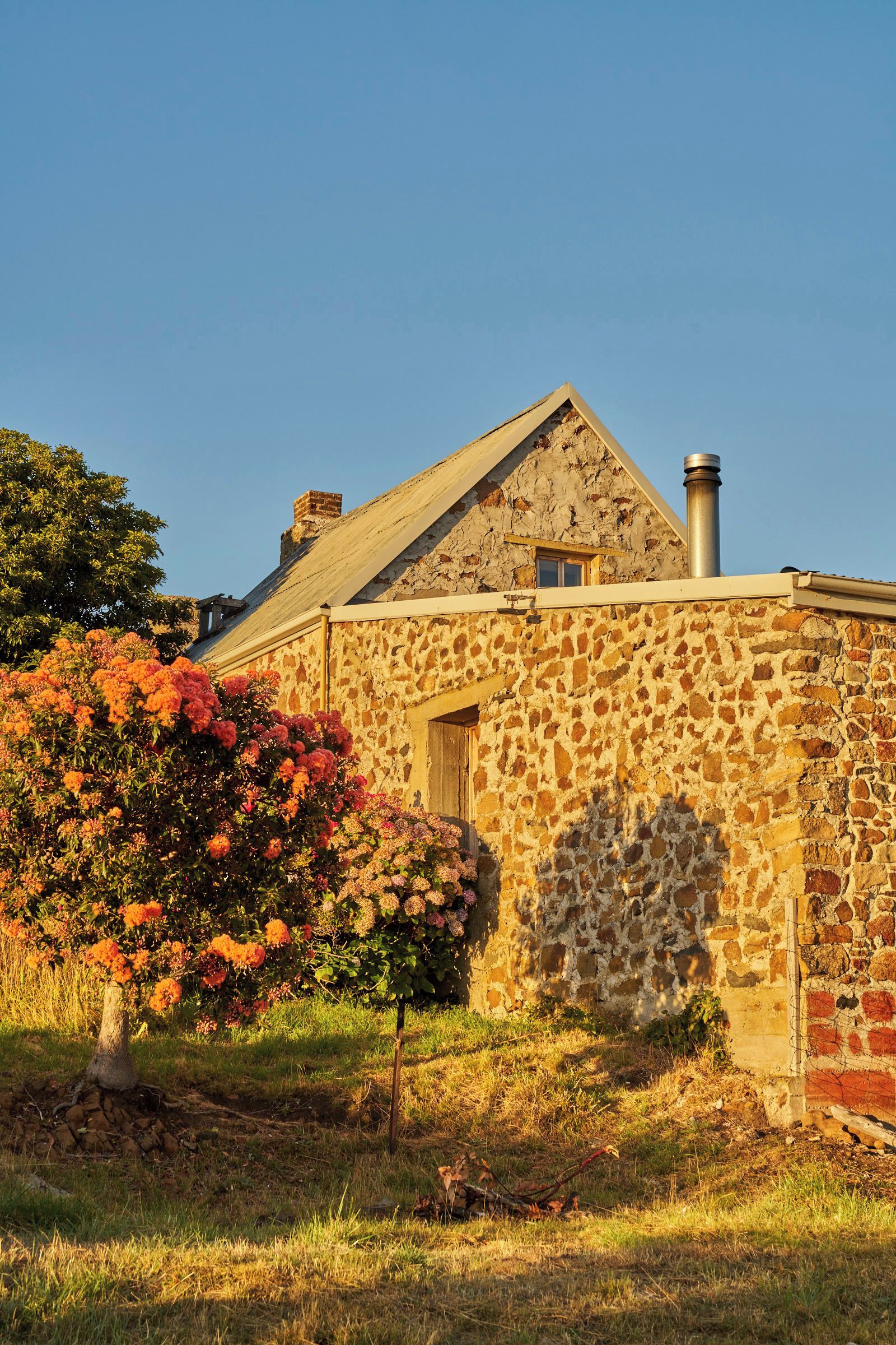 Un bâtiment en pierre avec un toit à pignon et une cheminée.