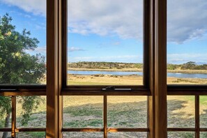 A window with a view of a natural landscape including trees, grass, and a body of water. - Shepherds Cottage at Lisdillon Estate (Little Swanport)
